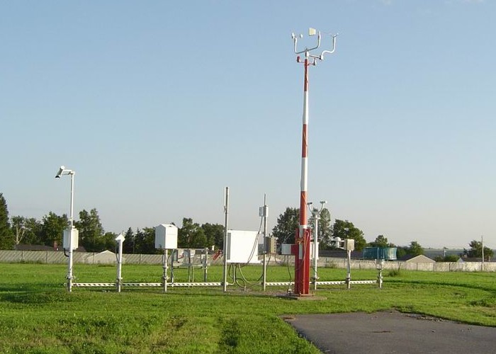 A collection of weather instruments alongside of a runway.