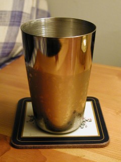 Metal cup half full of cold water. Condensation on cup clearly shows water level.